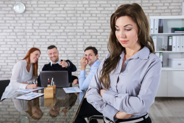 Colleagues Laughing To Her Coworker In Office