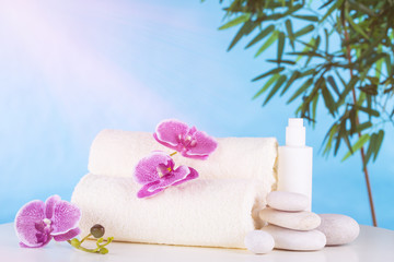 Spa. White towels, stones and orchids lie on the table, against the blue sky.