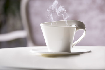 White cup and saucer. On a white table.