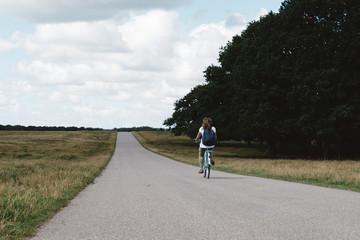 Obraz premium Smiling pretty young woman riding bike in a country road in the park