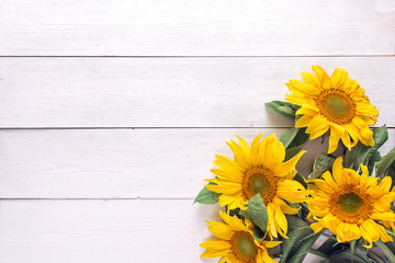 Background with a bouquet of yellow sunflowers on  white painted wooden planks. Space for text.