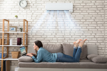 Woman Using Laptop Under The Air Conditioner