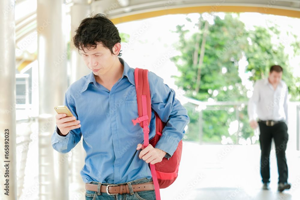 Aufkleber Businessman or tourist holding mobile using smartphone for texting sms message or find a location in map application on the path way building