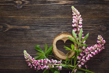 Pink lupine flowers and decorative wooden heart on dark wooden  background. Copy space.