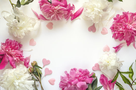 Frame of peonies and decorative hearts on white background. Place for text.
