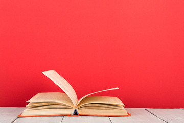 education and wisdom concept - open book on wooden table, color background