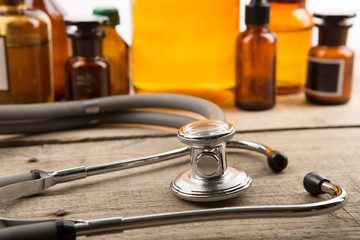 Workplace of doctor - stethoscope and pharmacy bottles on the wooden desk
