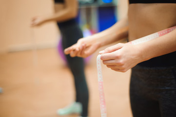 Young slim woman measuring waist using the tape measure.