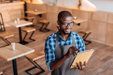 handsome smiling african american waiter taking order with digital tablet in coffee shop