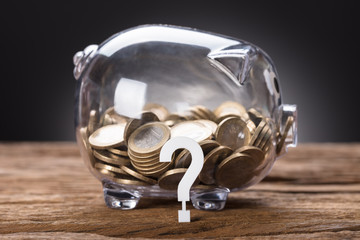 Question Mark And Coins In Transparent Piggy Bank
