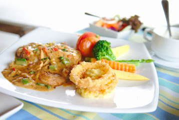 Steak with fried union and vegetable in white plate.