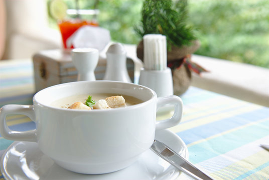 A cup of Soup and seasoning on the table