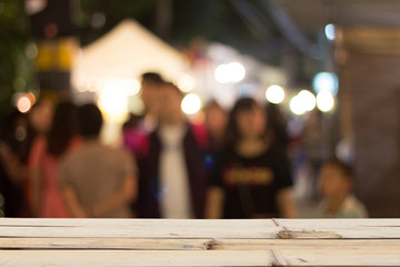 Blurred people on night street background and wooden tabletop on font