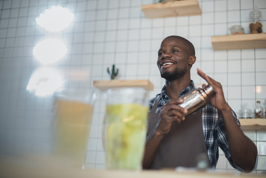 Smiling African American Bartender Making Cocktails With Shaker On Bar Counter In Cafe