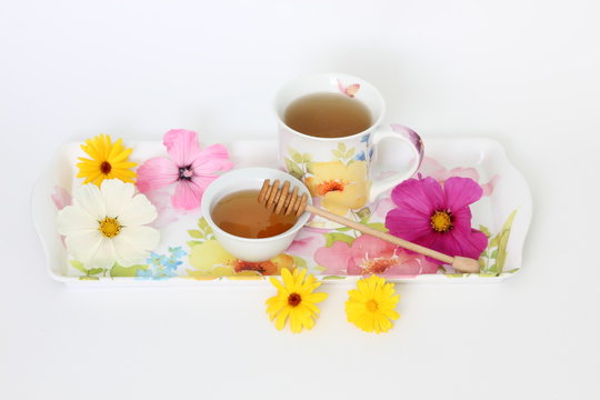 Cup of tea with honey on colourful tray 