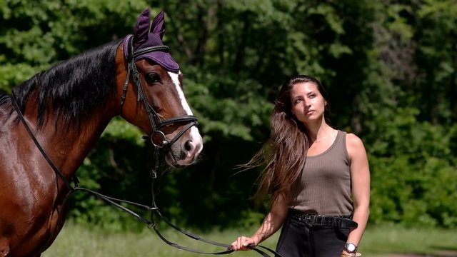 Girl moving long hair next to her horse in the forest