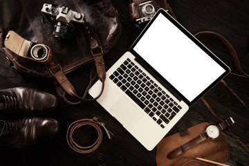 Laptop, old cameras, watch and leather bag od dark wooden board