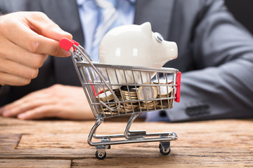 Businessman Pushing Piggybank And Coins In Shopping Cart