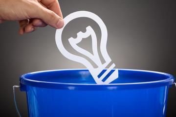 Businessman Throwing Paper Light Bulb In Blue Bucket