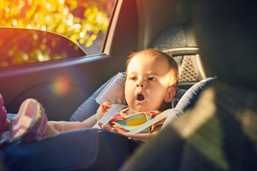 Close Up cute baby sitting in modern car seat. Child new born traveling safety on the road. Safe way to travel fastened seat belts in a vehicle with young kids. Trip with an infant.