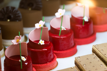 assorted colorful sponge cake in red flower decoration behind glass window