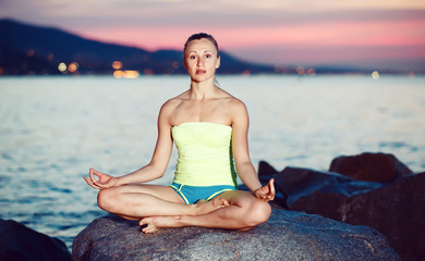 Fototapeta na wymiar Cross-legged female practice yoga at sunset sea shore