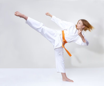 A kick with a foot is struck by a girl with an orange belt