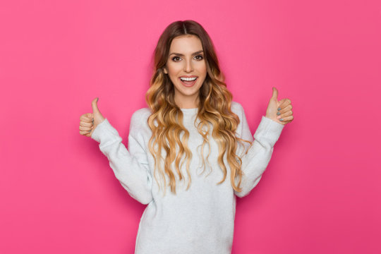 Happy Young Blond Woman In Pastel Sweater Is Showing Thumbs Up