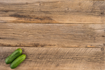 Two fresh cucumbers on an old wooden table.