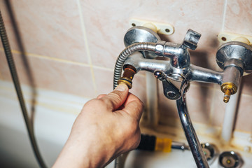 Man repair and fixing leaky old faucet in bathroom