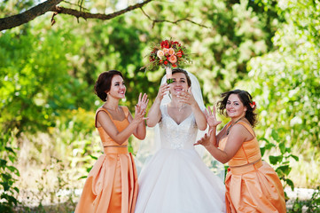Happy bride having fun with her cool fun bridesmaids in the park on a wedding day.