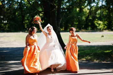 Happy bride having fun with her cool fun bridesmaids in the park on a wedding day.