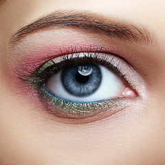 Obraz premium Closeup macro image of human woman eye with pink and green makeup