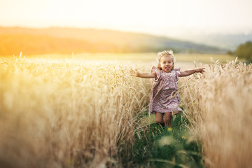 happy running girl on a wheat field in the sunlight