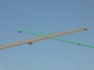 Two cranes green and blue with sky background