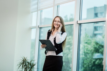 Fototapeta premium A businesswoman talking on a mobile phone,woman talking on the phone in office,Portrait of businesswoman talking on mobile phone,business concept