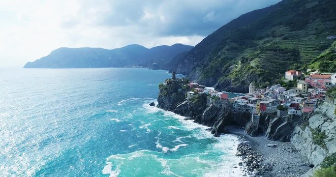 aerial view of travel landmark destination Vernazza,small mediterranean sea town, Cinque terre National Park, Liguria, Italy. Sunset with cloud and flare. 4k slow motion 60 fps drone backward video