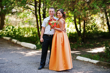 Gorgeous bridesmaid posing with groomsman in the park on the wedding day.