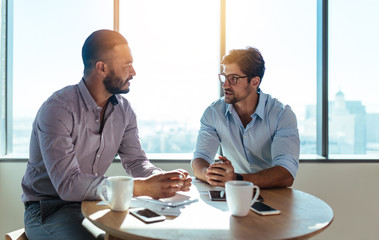 Business partners discussing business plans sitting at table in