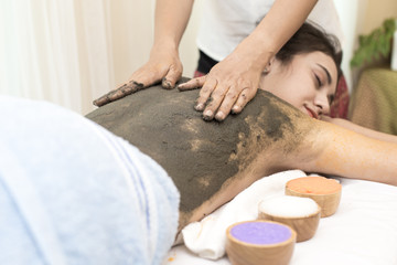 Beautiful Young Woman getting a mud massage at spa salon, health and healing concept.