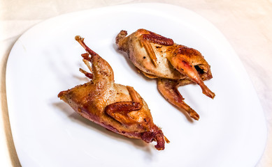 fried quail with fresh vegetables against white plate