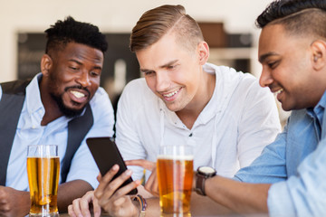 male friends with smartphone drinking beer at bar