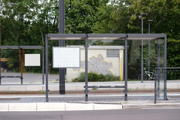 Straßenbahnhaltestelle / Der neue gebaute Glasunterstand einer Straßenbahnhaltestelle an einer Straße.