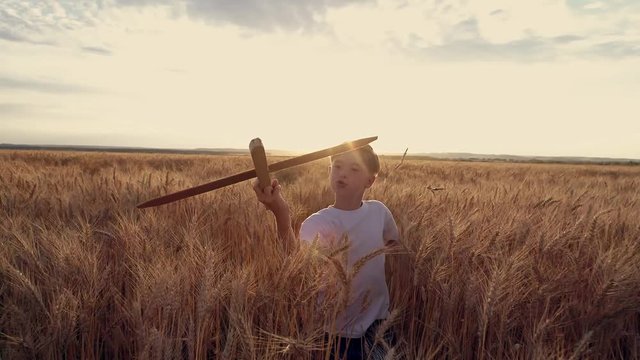 Happy child runs with a toy airplane on a sunset background over a wheat field
