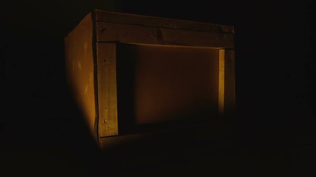 Wooden box illuminated by fire burning in darkness, homeless warming center