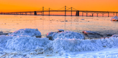 sunrise by Chesapeake Bay Bridge in winter with icebergs and snow and ice on shoreline