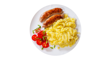 fried meat sausages with mashed potatoes and vegetables salad in a plate. top view. isolated on white