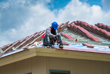 Workers are drilling roof tiles with a drill.