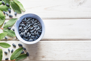 Ripe berries of a honeysuckle on a wooden background. Summer harvest.