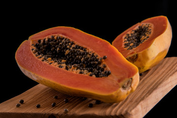 Freshness papaya fruit on the wooden plank and black background. Horizontal version.